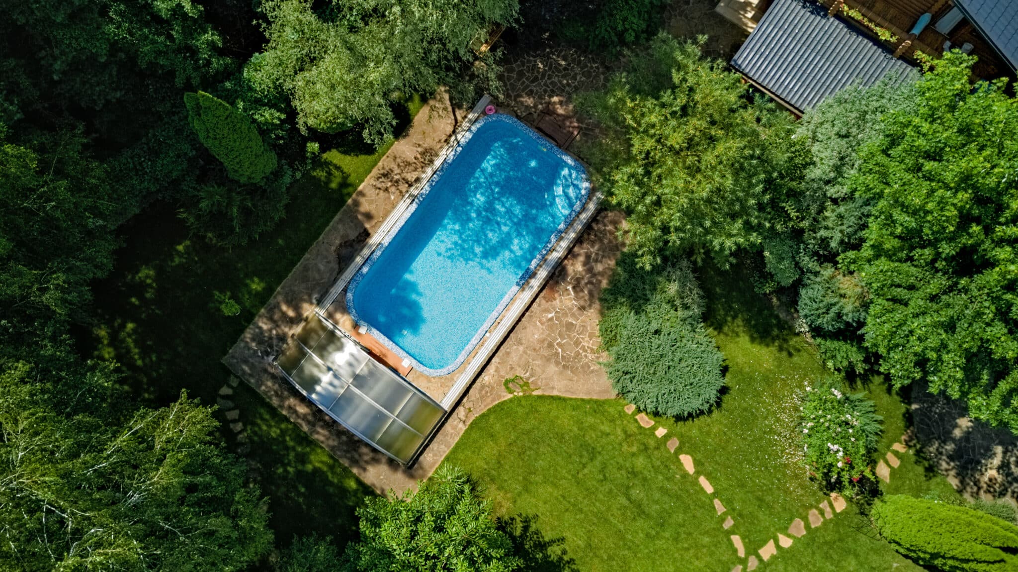 Rechteckiger Pool von oben, umgeben von Rasen und Bäumen