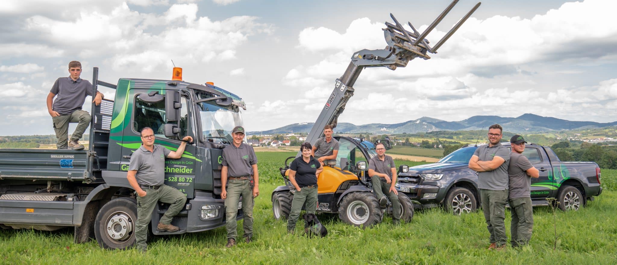 Das Team von Gartenbau Schneider mit Fahrzeugen auf der Wiese